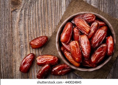 Bowl of dried dates on wooden background from top view