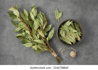Bowl of dried laurel leaves and bunch of dry green bay leaves, top view, flat lay. 