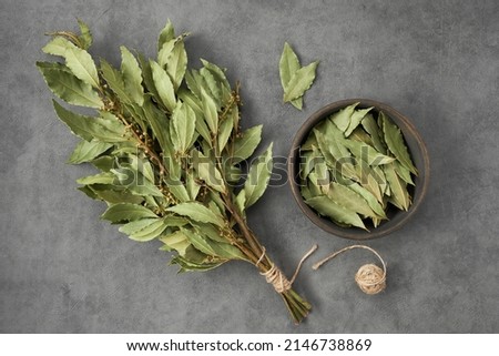 Bowl of dried laurel leaves and bunch of dry green bay leaves, top view, flat lay. 