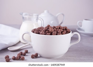 A bowl of dry chocolate balls cereal and bottle if milk on the gray table for health breakfast