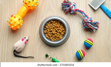 Bowl Of Dry Food For Cat Or Dog And Pet Accessories On Wooden Table, View From Above. Pet Care And Training Concept.
