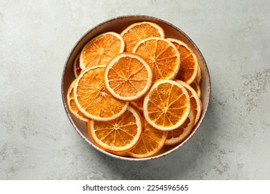 Bowl of dry orange slices on light table, top view