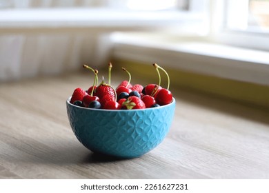 Bowl filled with fresh blueberries, cherries and strawberries on wooden table. Selective focus. - Powered by Shutterstock