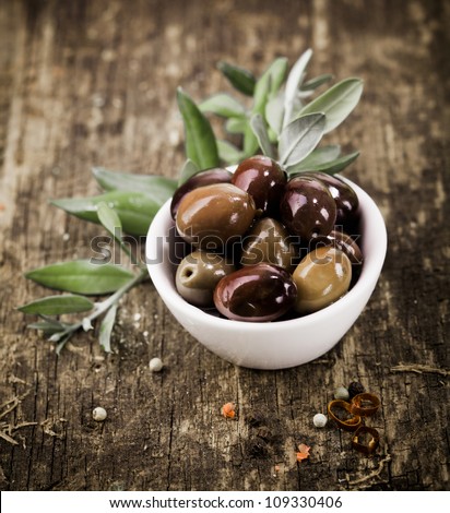 Bowl filled with freshly harvested whole fresh black olives on a rustic wooden tabletop