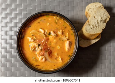 Bowl Of Fish Soup With Pieces Of White Bread On The Side.