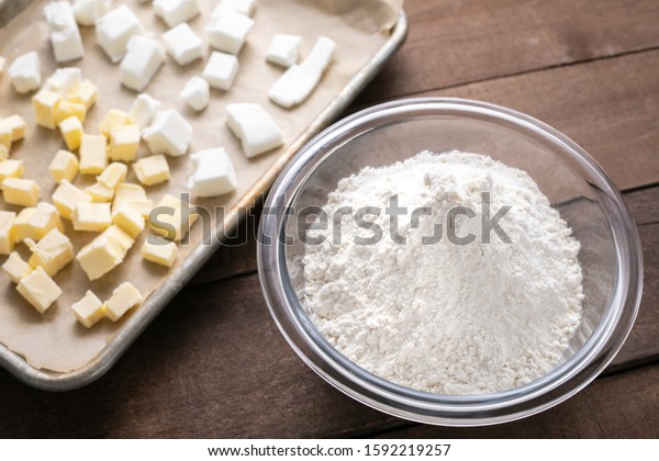 Bowl of flour beside a sheet pan with vegetable\
shortening and butter