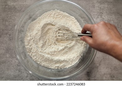 A bowl with flour and other dry baking ingredients being mixed with a whisk. Combining dry baking ingredients together. - Powered by Shutterstock