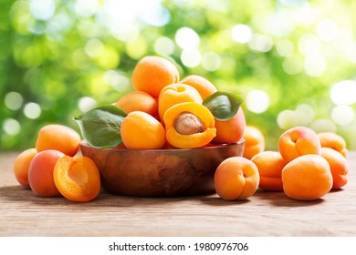 Bowl of fresh apricots on a wooden table over blurred green background