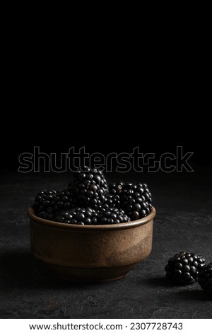 Bowl with fresh blackberries on a dark background. Concept of healthy food and lifestyle. Macro photography of blackberries. Closeup view. Dark food photography