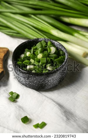 Bowl with fresh cut green onion on table
