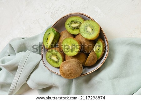 Bowl with fresh cut kiwi on light background