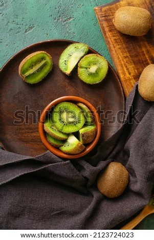 Bowl with fresh cut kiwi on green background