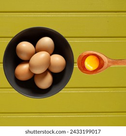 Bowl of fresh eggs with a spoon and vibrant yolk, ready for cooking or baking. Symbol of wholesome ingredients and culinary preparation. - Powered by Shutterstock