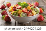 A bowl of fresh fruit salad featuring strawberries, kiwi, and pineapple, set on a rustic wooden table.