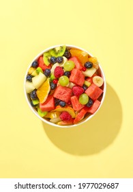 bowl of fresh fruit salad isolated on yellow background, top view - Shutterstock ID 1977029687