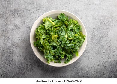 Bowl of fresh green chopped kale on gray rustic stone background, top view, close-up. Ingredient for making healthy salad. Clean eating, detox or diet concept  - Powered by Shutterstock