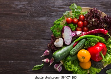 Bowl With Fresh Organic Vegetables And Greens On Wood Background. Healthy Natural Food On Rustic Table With Copy Space For Menu Or Recipe. Tomato, Carrot And Other Cooking Ingredients Top View