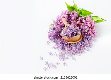 Bowl of fresh purple lilac petals with a branch of blooming lilac on a white background. Lilac flowers fragrance. Concept for spa and aromatherapy.
