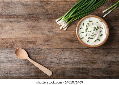 Bowl Of Fresh Sour Cream With Green Onion And Spoon On Wooden Table, Flat Lay. Space For Text