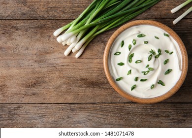 Bowl Of Fresh Sour Cream With Green Onion On Wooden Table, Flat Lay. Space For Text