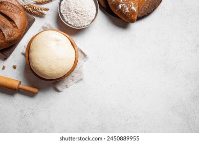 Bowl of fresh yeast dough with flour, rolling pin and fresh sourdough bread on white background, top view, copy space. Baking, pastry and kneading concept. - Powered by Shutterstock