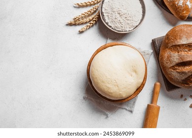 Bowl of fresh yeast dough with flour, rolling pin and fresh sourdough bread on white background, top view, copy space. Baking, pastry and kneading concept. - Powered by Shutterstock