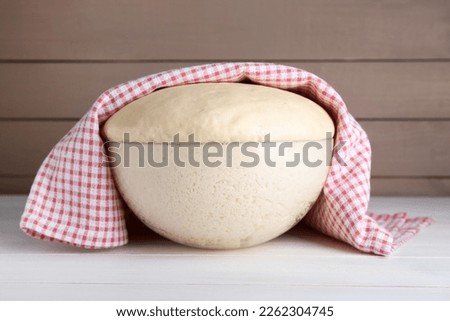 Bowl of fresh yeast dough on white wooden table