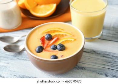 Bowl Of Fresh Yogurt Smoothie With Orange And Berries On Wooden Background