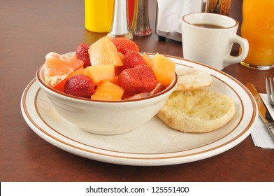 A Bowl Of Fruit With A Buttered English Muffin