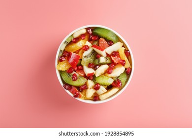 Bowl with fruit salad on a pink background. Juicy and ripe fruit slices. Top view - Powered by Shutterstock