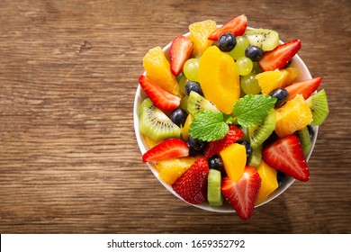 Bowl Of Fruit Salad On A Wooden Table, Top View