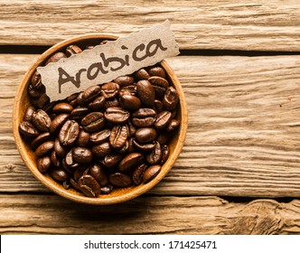 Bowl full of Arabica coffee beans over an old wooden table