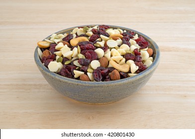 A Bowl Full Of An Assortment Of Nuts And Dried Cranberries Trail Mix On A Wood Table Top.