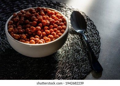 Bowl full of chocoball cereal with light beam hitting the table.