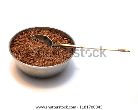 Bowl full of fresh, healthy organic common flax seeds with a vintage silver spoon dipped in 