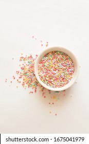 A Bowl Full Of Rainbow Sprinkles, On A White Background