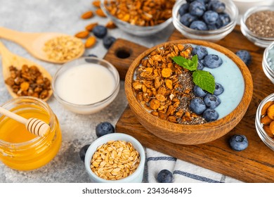 Bowl of granola with yogurt and fresh berries on a texture table. Yogurt berries, acai bowl, spirulina bowl. Healthy food, balanced breakfast. Strawberries, blueberries, kiwi, peach, almonds and chia. - Powered by Shutterstock