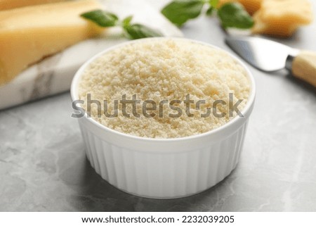 Bowl with grated parmesan cheese on light table, closeup