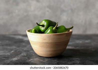 Bowl with green jalapeno peppers on grey background