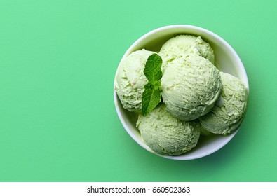 Bowl Of Green Pistachio Ice Cream Isolated On Green Background. Top View