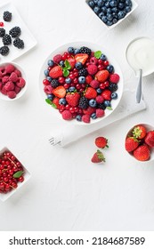Bowl of healthy fresh berry fruit meal with cream on white background. Top view. Berries overhead closeup colorful assorted mix of strawberry, blueberry, raspberry, blackberry, red currant