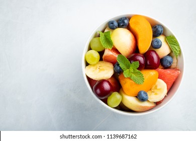 Bowl Of Healthy Fresh Fruit Salad On A White Background. Top View With Copy Space. Flat Lay