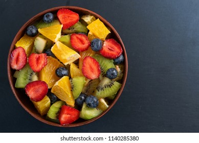 Bowl Of Healthy Fresh Fruit Salad On Dark Background. Top View