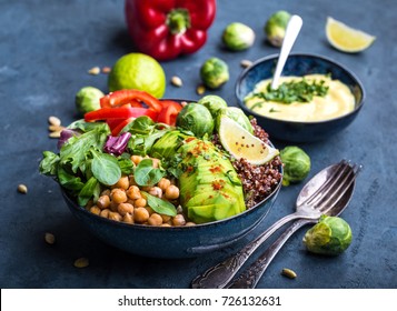 Bowl with healthy salad and dip. Close-up. Buddha bowl with chickpea, avocado, quinoa seeds, red bell pepper, fresh spinach, brussels sprout, lime mix. Vegetarian salad. Clean healthy eating concept