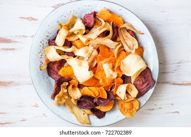 Bowl of Healthy Snack from Vegetable Chips, such as Sweet Potato, Beetroot, Carrot, Parsnip on Light Wooden Background - Powered by Shutterstock