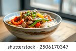 A bowl of hearty beef stir-fry, complete with vibrant slices of bell pepper and sugar snap peas, atop a bed of steamed white rice