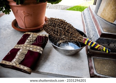 Bowl with holy water, holy basil with the tricolor and some priest's clothes.