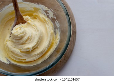 Bowl of home made buttercream frosting with wooden spoon and white background for copy space
