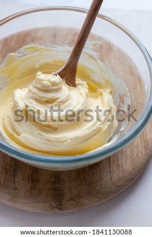 Bowl of home made buttercream frosting with wooden spoon
