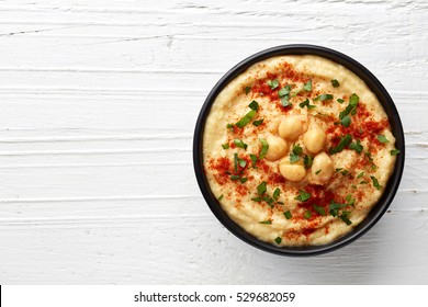Bowl of homemade hummus on white wooden background from top view - Shutterstock ID 529682059